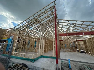 Construction site with partially built wooden house frames and a clear sky in the background.