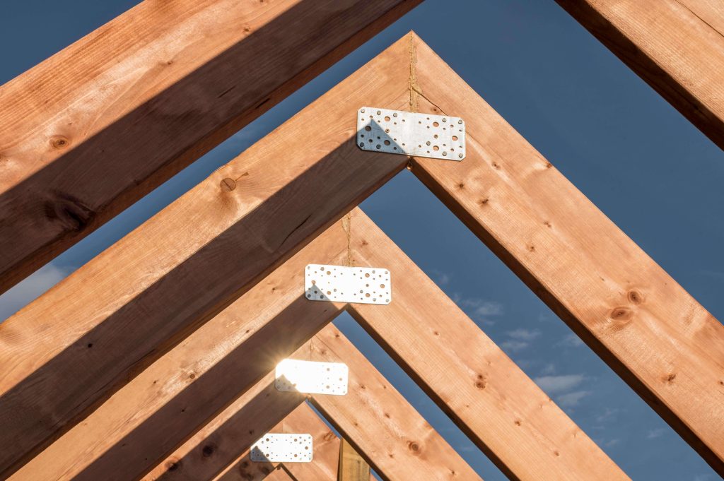 Front view of a house under construction with visible wooden roof framing.