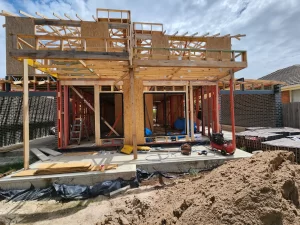 Construction site with multiple wooden house frames in progress, showing workers and building materials.